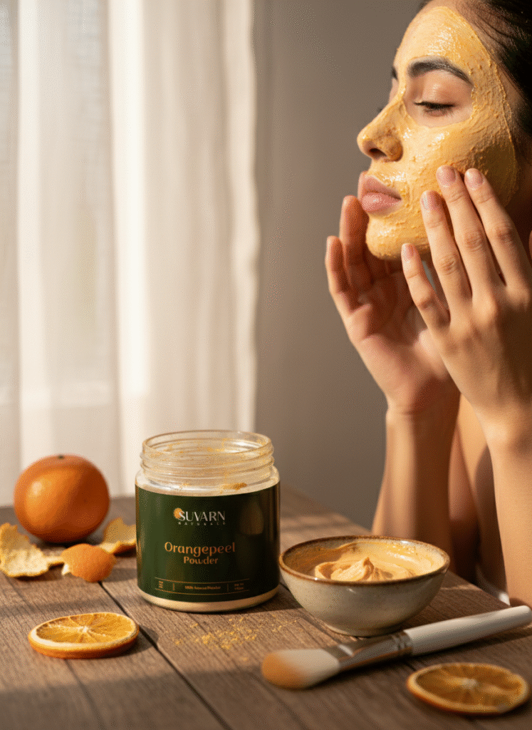 Woman applying natural orange peel powder face mask from Suvarn Naturals jar, DIY herbal skincare for glowing skin, brightening and tan removal treatment at home.